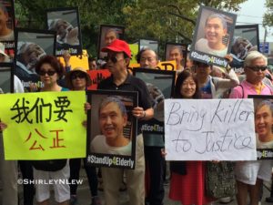 Members of the senior center and the community hold signs in the rally for justice for Mr. Tse.